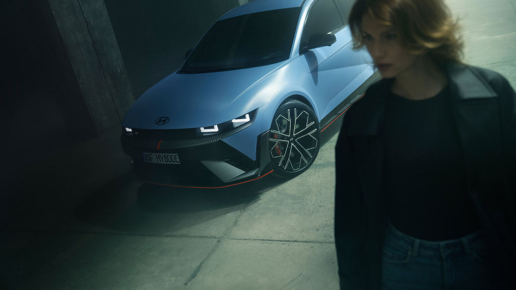 The all-new Hyundai KONA Electric in blue with a woman walking behind it.